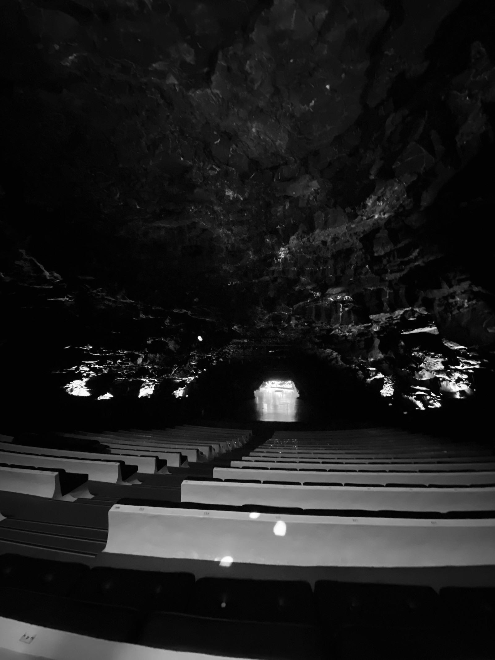 Auditorio de los Jameos del Agua visto desde las filas más altas: las gradas blancas descienden hacia la abertura de la cueva, bajo la bóveda de basalto.